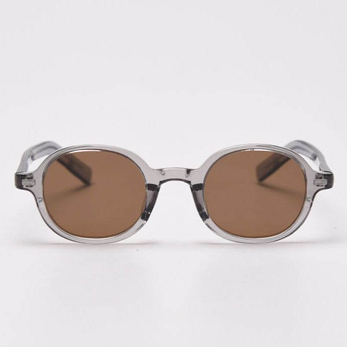 Round sunglasses with transparent frame and brown lenses on a white background